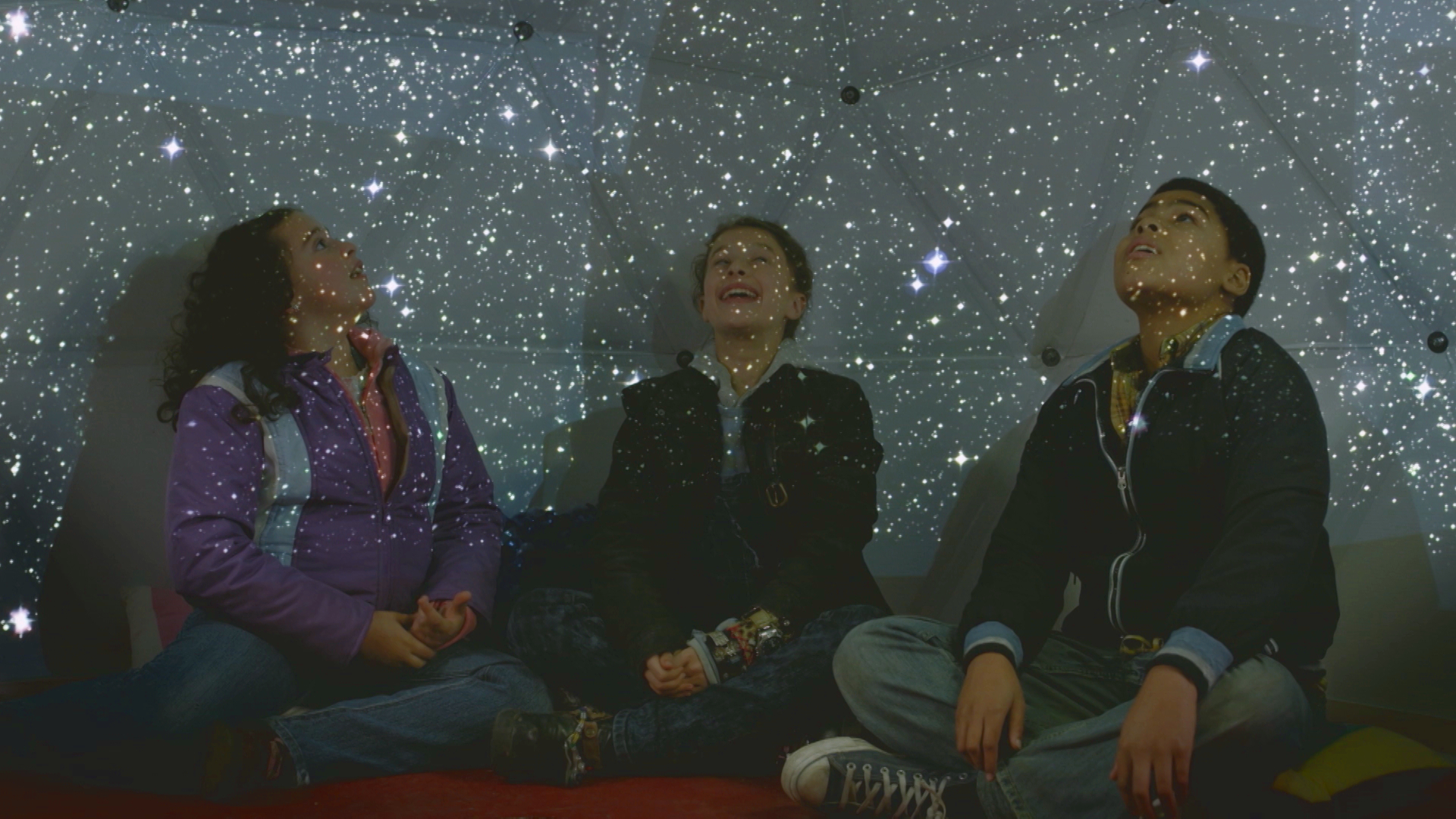 Sofia, Ana e Nick observam as estrelas em um planetário