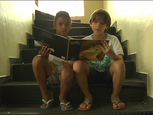 Voluntário em um abrigo em Nova Friburgo, Rudáh (à direita) acompanha a leitura junto a Bruno, que perdeu a casa na enchente