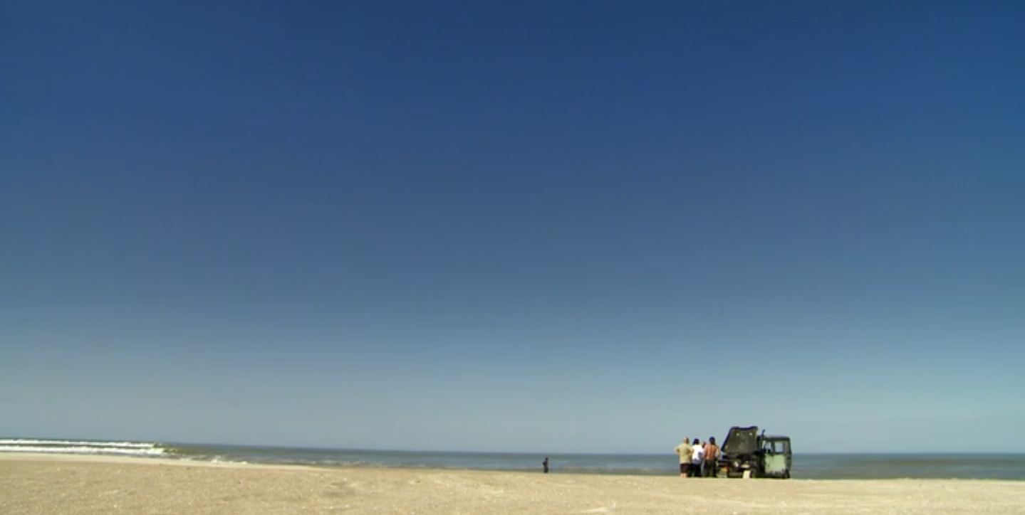 Carro parado na areia de uma praia vazia
