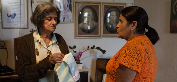 Benzedeira Isabel do Augusto na sala da sua casa, fazendo a bênção "costura no pano" – Morro do Ferro (MG). Foto: Luisina López Ferrari.